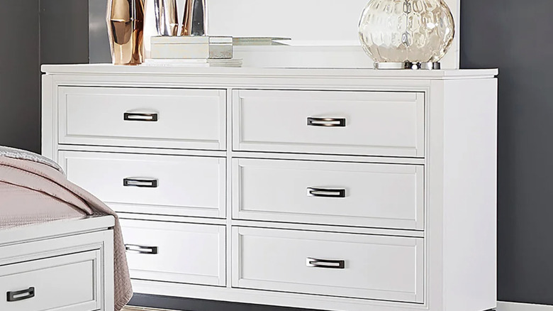 The Norah dresser and mirror next to the matching bed against a gray wall