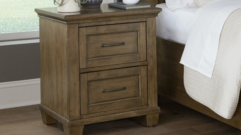The Pierson nightstand next to a bed under a window