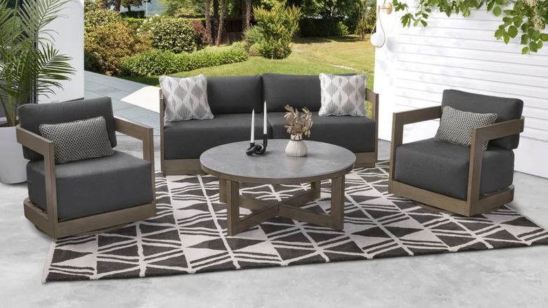 A gray modern patio set with a sofa, two chairs, and a round table