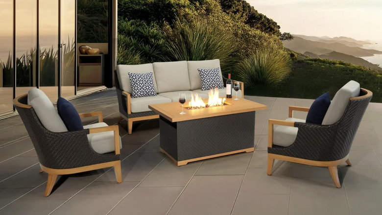A wood and black rattan patio set with a fire table
