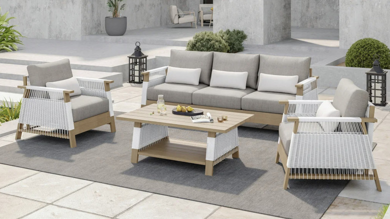 A white and light wood rattan patio set in front of a concrete home