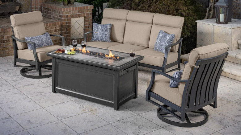A beige and black outdoor patio set with a fire pit table