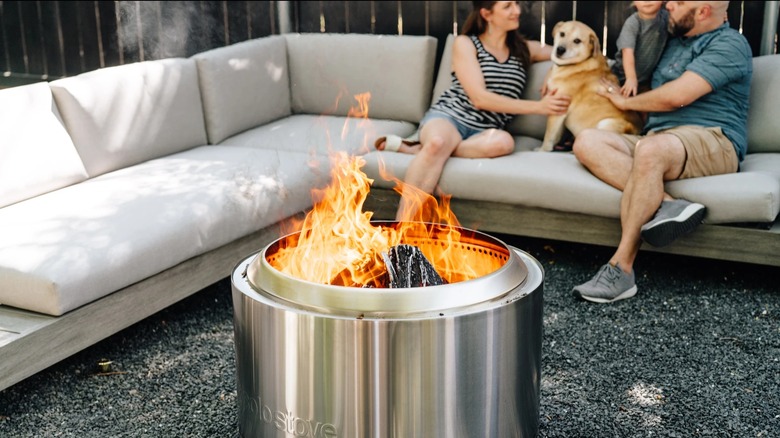 A family on an outdoor couch by a Solo Stove fire pit