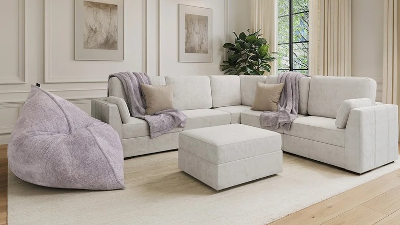 A gray couch with lilac throws on it in a living room