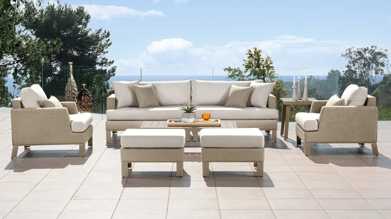 An outdoor sofa set with beige bottoms and white seat cushions