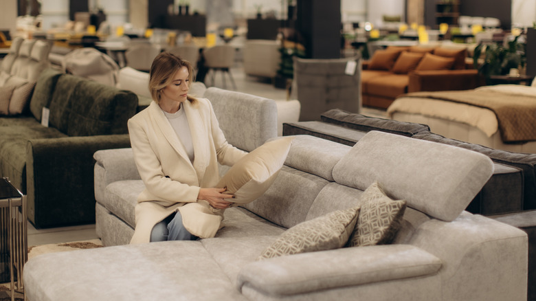 Woman sitting on a couch and examining a pillow in a furniture store