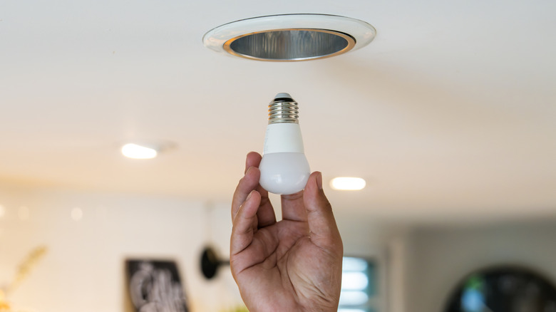 A man inserting an LED light bulb into a ceiling fixture
