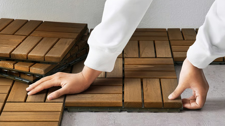 Person snapping together the RUNNEN deck tiles from IKEA