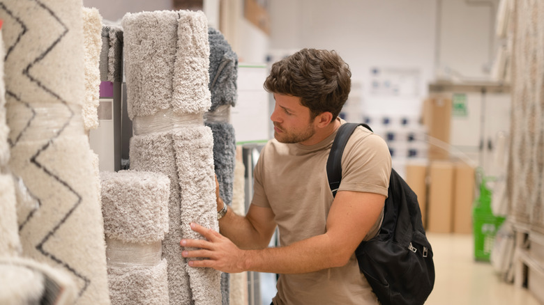 A young man shops for a neutral toned rug