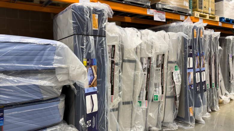 An aisle of mattresses wrapped in plastic for sale at Costco