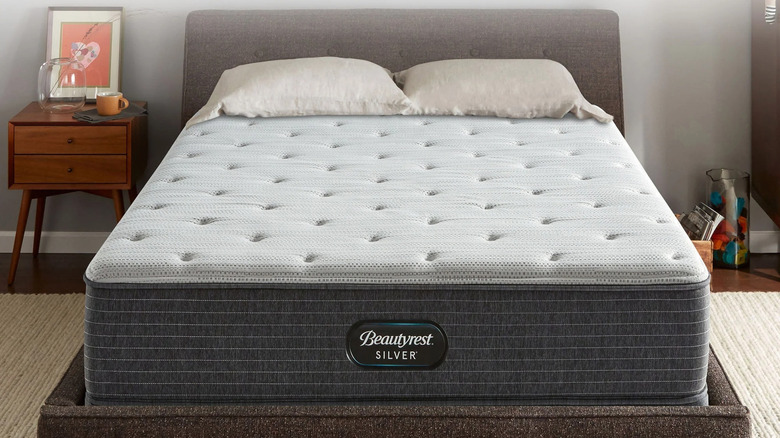An unmade Beautyrest 12" Silver BRS900 Medium-Firm Mattress in a bedroom