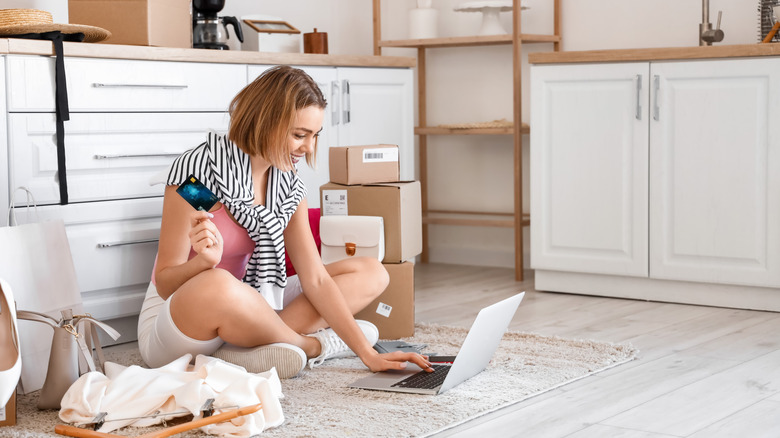 Person on the floor in the kitchen, shopping online on a laptop
