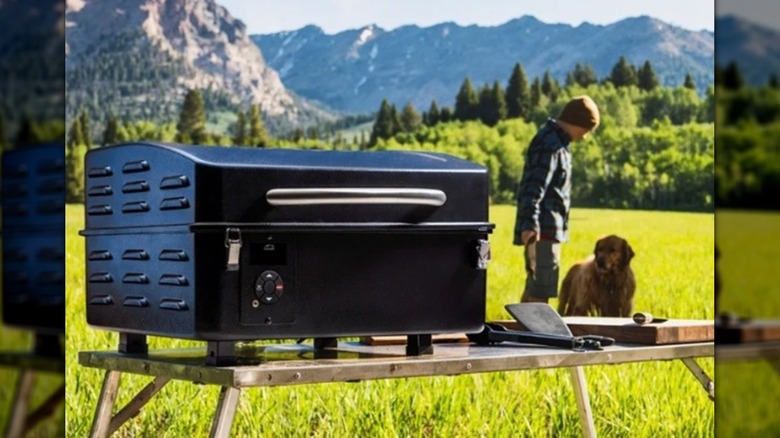 Man using a portable pellet grill at a campsite