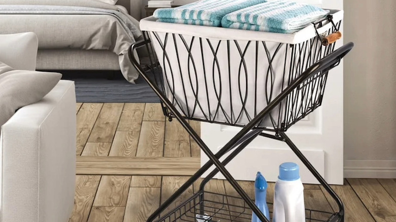 A laundry cart full of folded towels and carrying laundry detergent