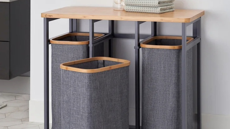 A laundry station with three hampers and a wooden top.