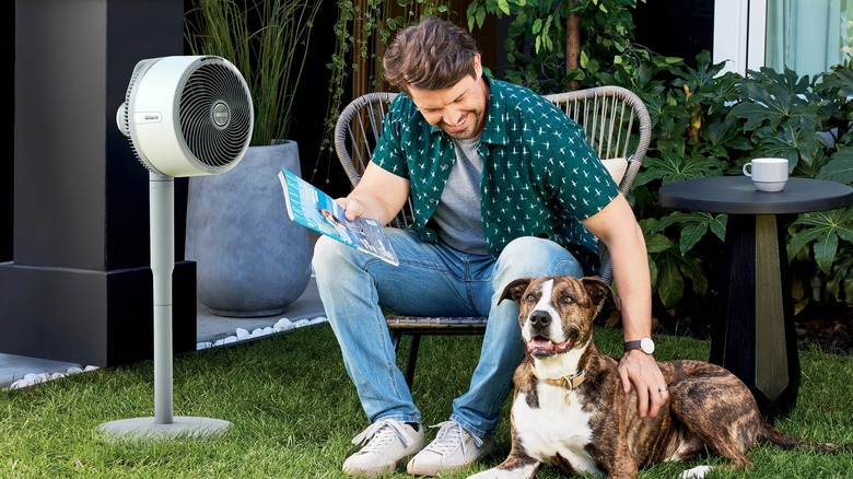 Man and dog sitting outside with the Shark FlexBreeze Cordless Fan