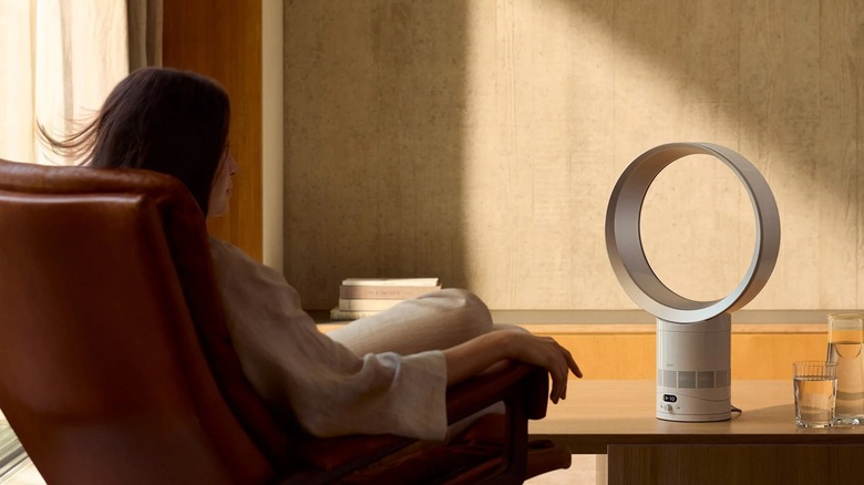 A woman sitting in a chair with the Dyson Cool CF1 Bladeless Fan on a table