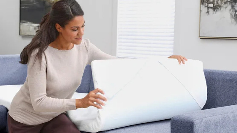 A woman setting up a spare bed on her Flexsteel couch using the Flexsteel mattress topper