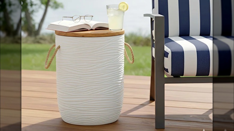 The Stylecraft outdoor storage table with a glass of lemonade, a book, and glasses laid on top