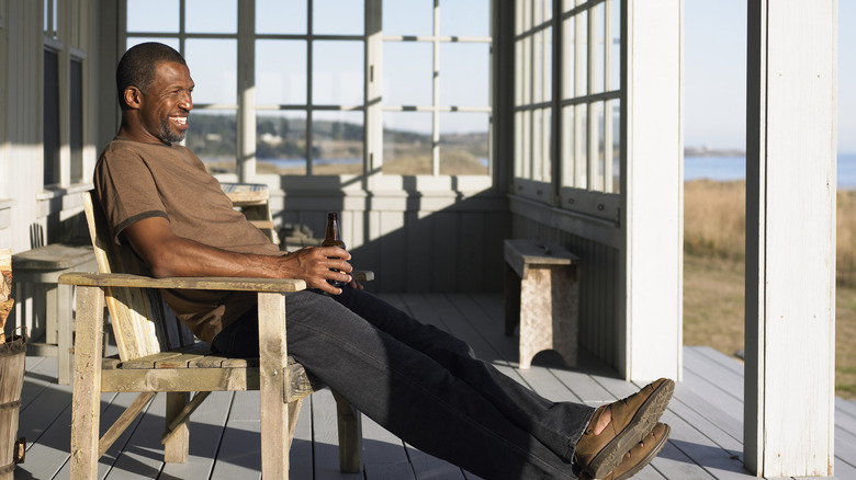 A smiling man is sitting on his porch in the sun