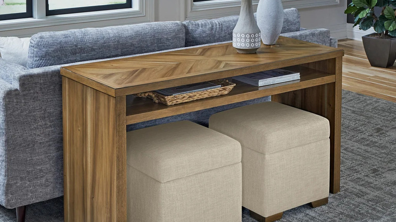 The Universal Broadmoore Zealand Sofa Table behind a blue-gray couch in a living room