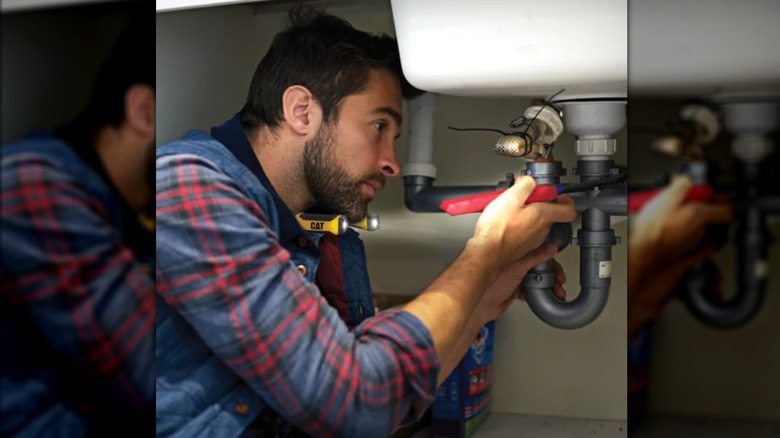 man wearing neck flashlight to repair plumbing