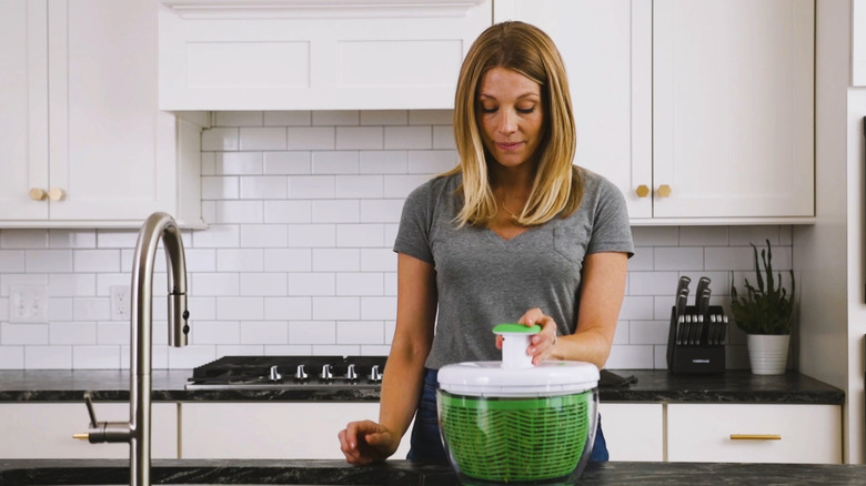 woman using pump activated salad spinner on kitchen counter