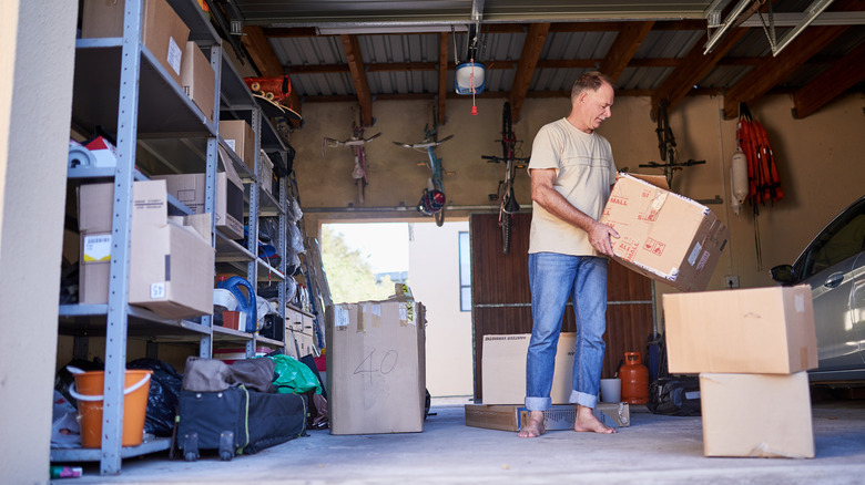 A man carrying boxes in a cluttered garage