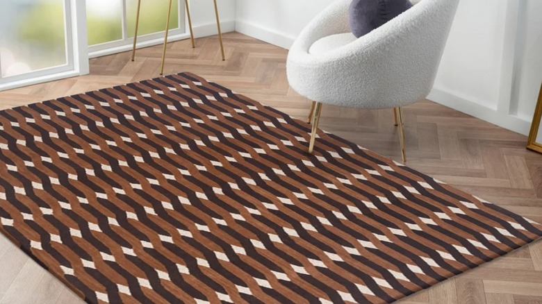 The Obeetee geometric wool rug stretched across floor in front of a sliding glass door by a small white chair