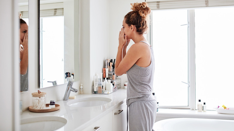 Woman holding nose in bathroom