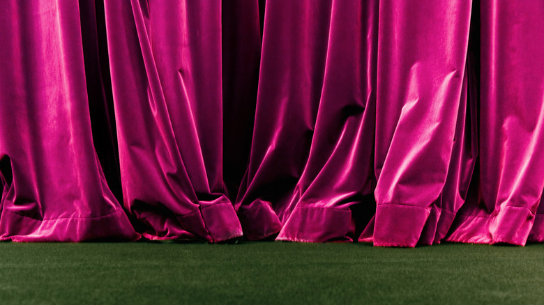 red velvet curtain against green carpeted floor