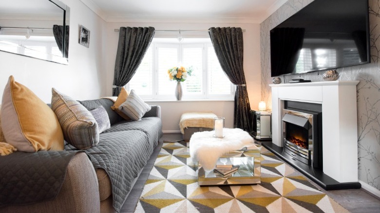 Large sofa with cover in living room opposite TV mounted over fireplace