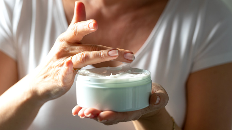 Woman dipping into cream jar