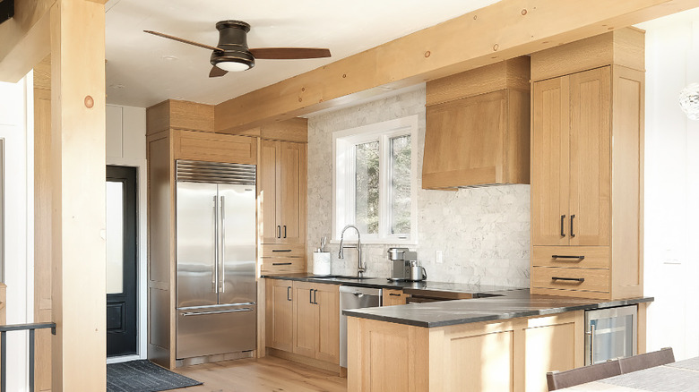 An oak kitchen with brown countertops and a large stainless steel fridge.