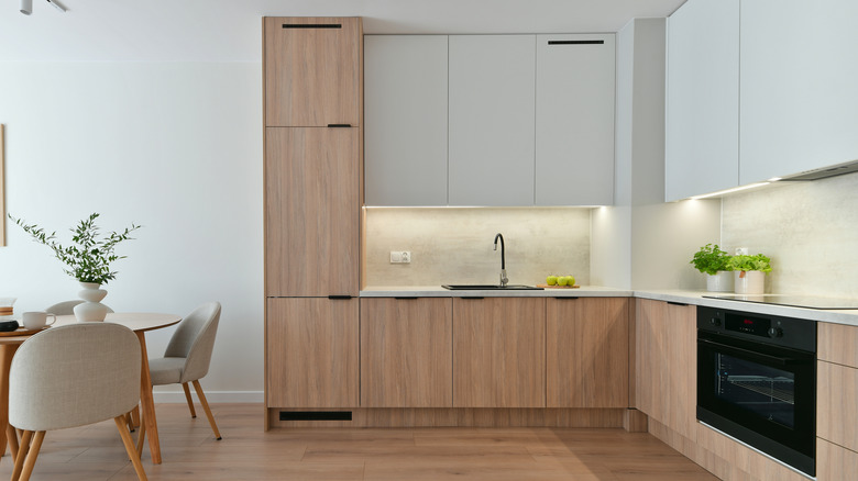 A white oak kitchen space with sink and over, along with some white painted cabinets.