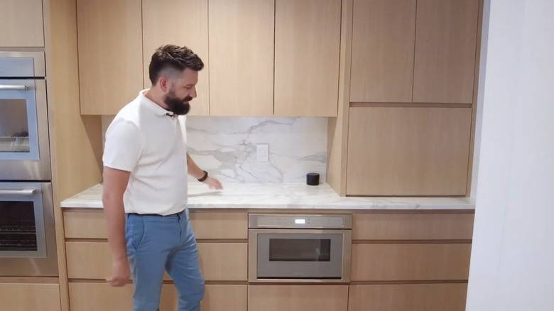 A marbled white kitchen island with marbled white backsplash and white oak cabinets