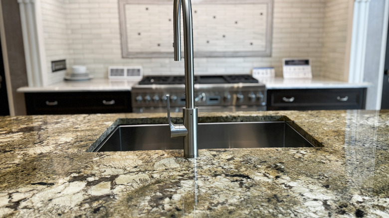 Close-up of a kitchen island with a sink and busy patterned countertop