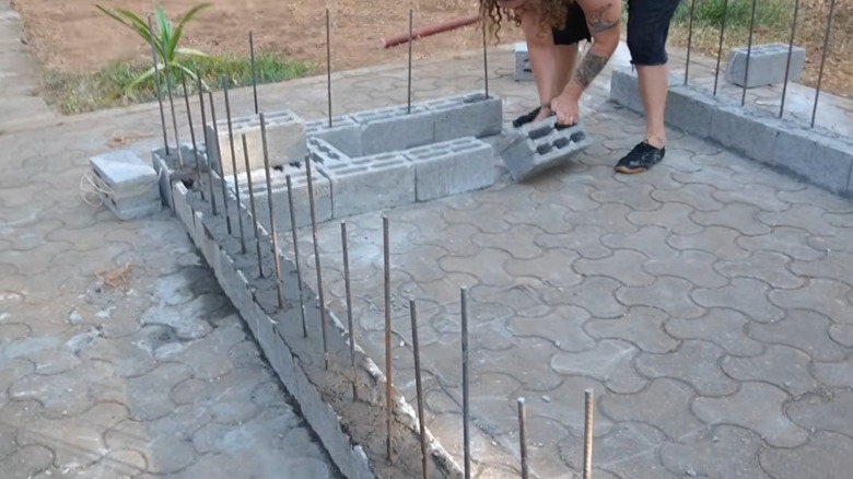 A person building a wall out of stacked concrete blocks