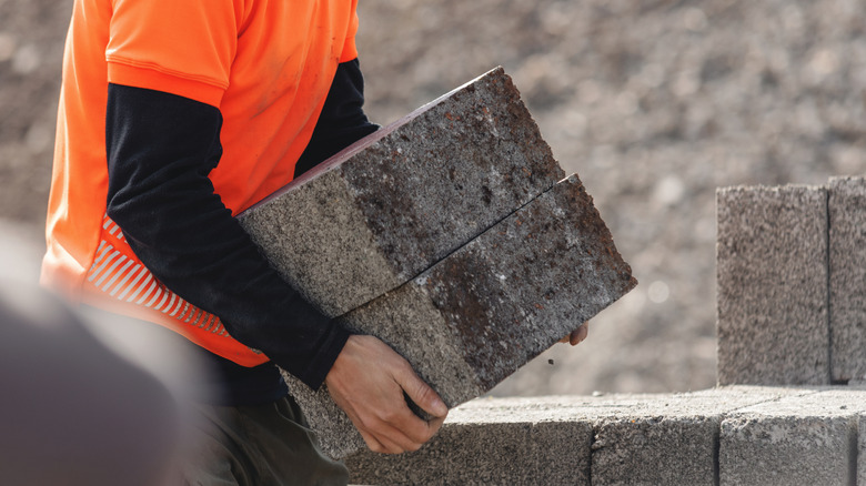 A person carrying concrete blocks