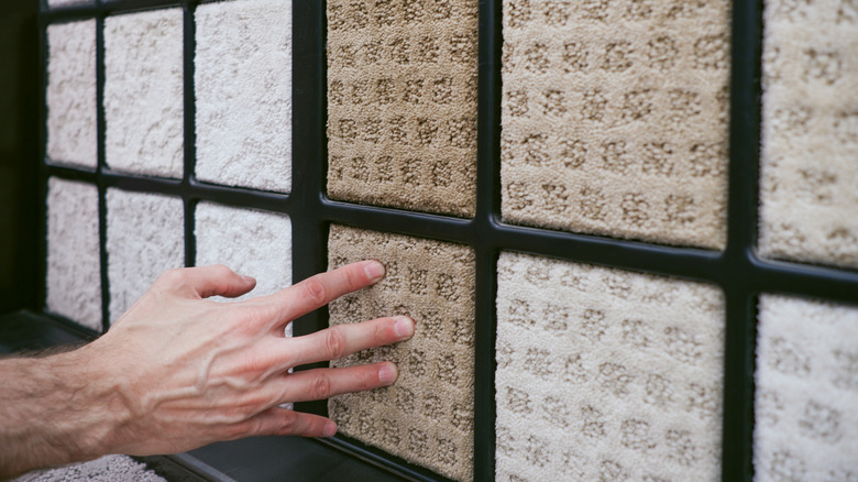 Person touching square carpet samples