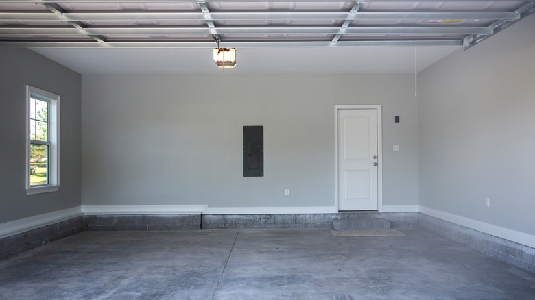 A view from inside a large house garage with cement flooring