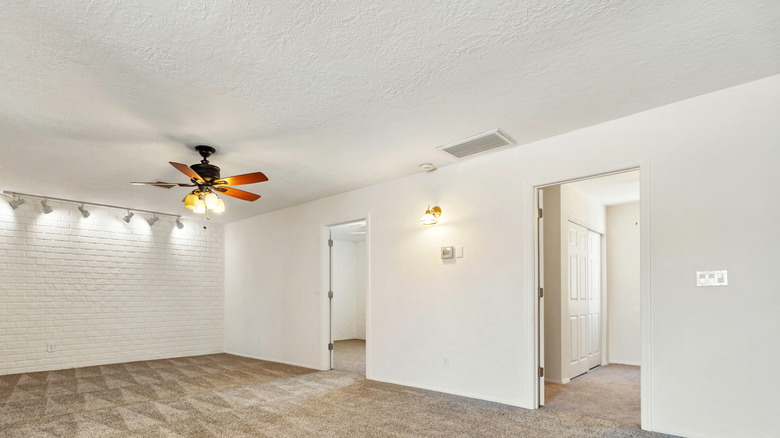 A room with light fixture and white popcorn ceiling.