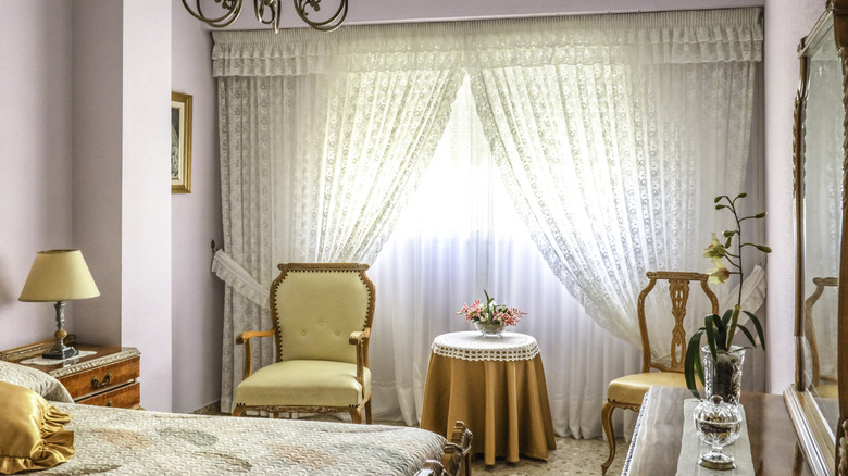 Lace curtains in front of a large window or sliding doors in a bedroom.
