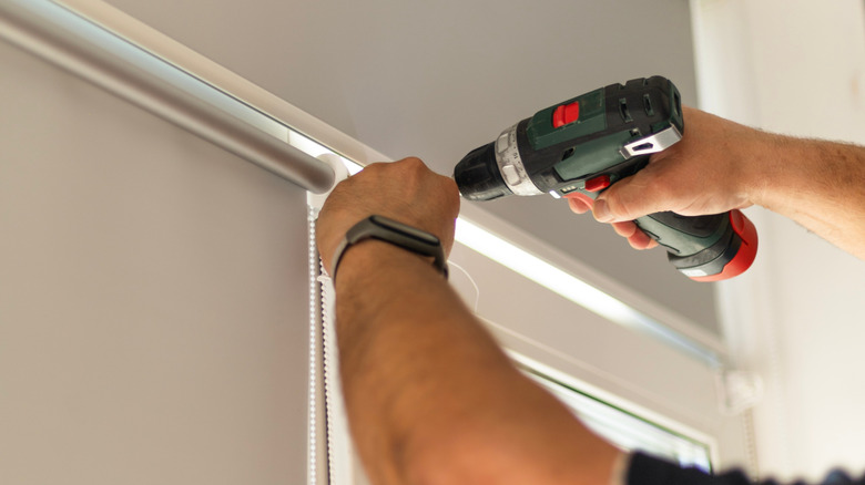 Hands installing a roller shade over a door
