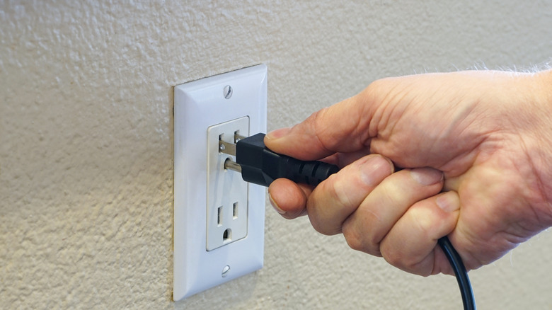 Hand putting plug into outlet