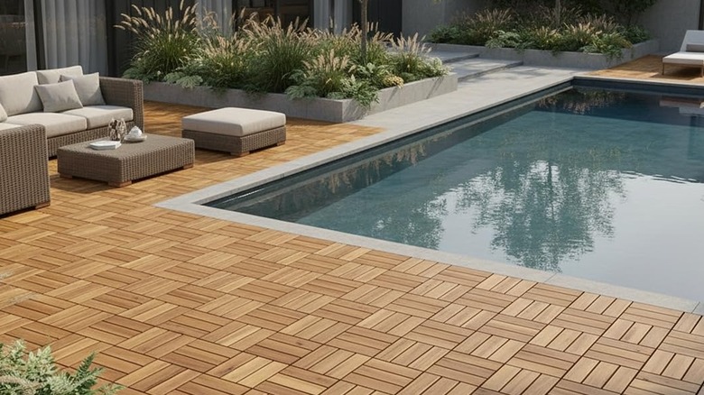 The interlocking wood tiles by Thyoi used on a patio surrounding a pool with furniture on top