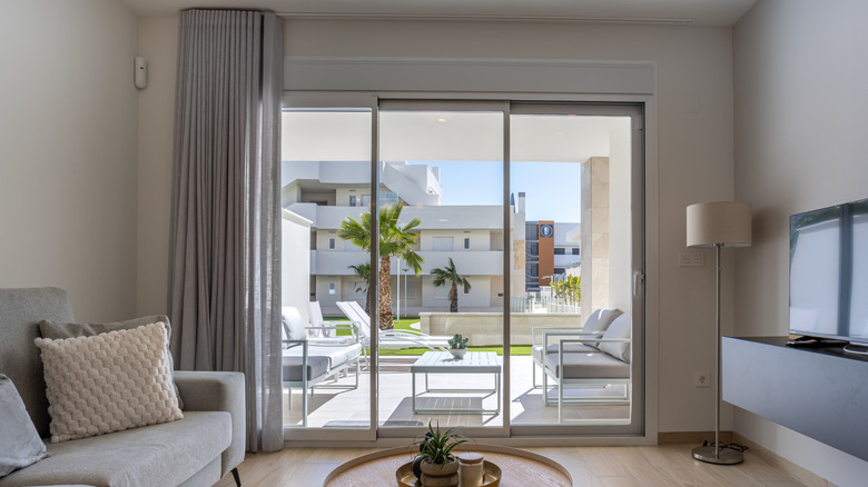 Sliding glass doors with an opened shade revealing light on the backyard