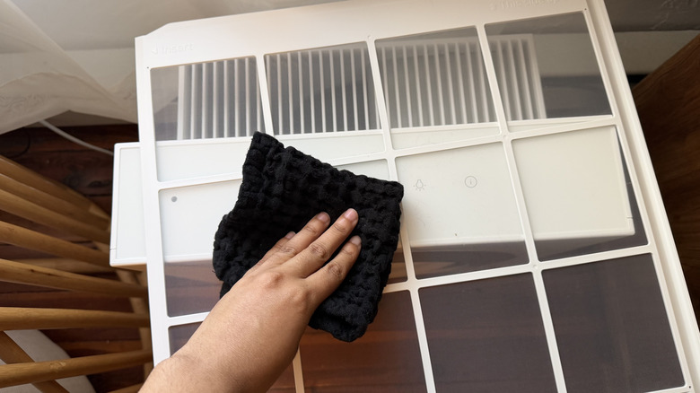 Hand wiping the pre-filter of the Airmega Mighty 2 with a black cloth