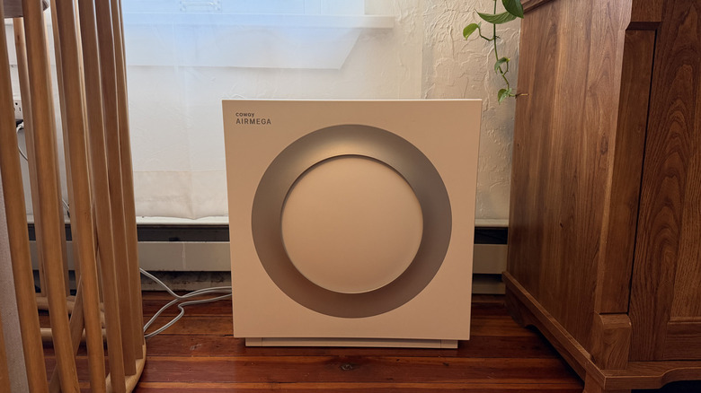 The Airmega Mighty2, between two pieces of wood furniture and a plant