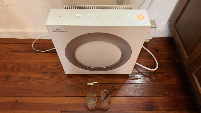 The Airmega Mighty2 with an incense burner on the floor in front of it and a red air quality reading